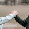 Two adults holding hands in an outdoor park setting, symbolizing trust and connection.